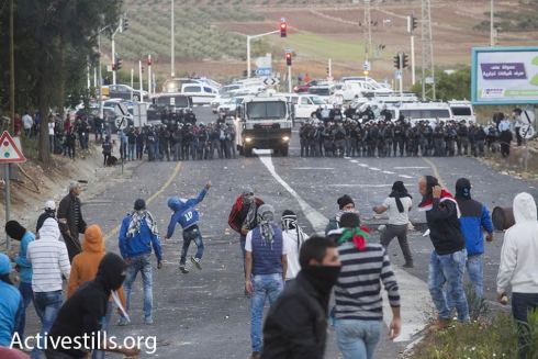Arab youth clash with Israeli riot police in Kafr Kanna, Israel. The protests come less than a day after an Arab man from the village was shot and killed by Israeli policemen. Security cameras caught the man attempting to attack the policemen, as well as the shooting, which took place after the man had already backed away considerably. (photo: Oren Ziv/Activestills.org)